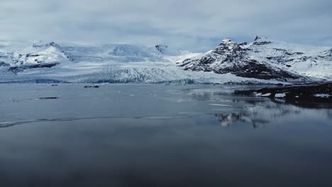 Snowy-rocky-mountains-at-lakeside-on-winter-day