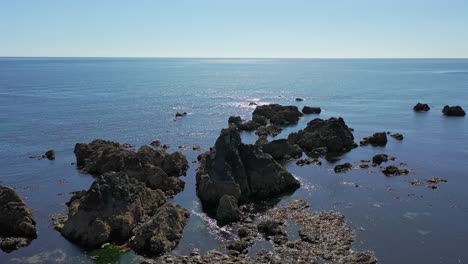 aerial orbiting view of rocks and rocky coastline in the south of ireland in summer with clear calm water