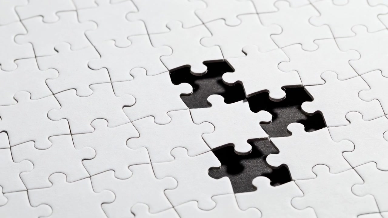 Telecamera in panoramica che rivela un puzzle bianco su un tavolo, evidenziando un vuoto nero di quattro pezzi e segni di matita.