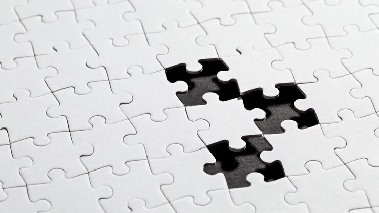 Panning camera revealing white jigsaw on table, highlighting four-piece black void and pencil marks