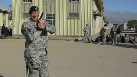 A-soldier-draws-a-hand-gun-then-points-to-a-patch-on-his-arm