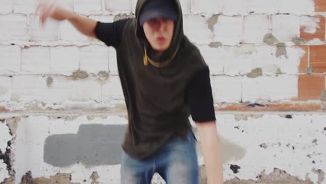 man hip hop dancing outside in city in front of brick wall