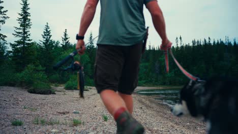 un hombre y su perro malamute de alaska caminando por el lago en indre fosen, noruega - toma amplia