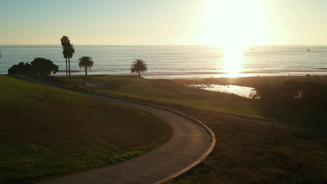 vista aérea del campo de golf con vista al mar durante la puesta de sol