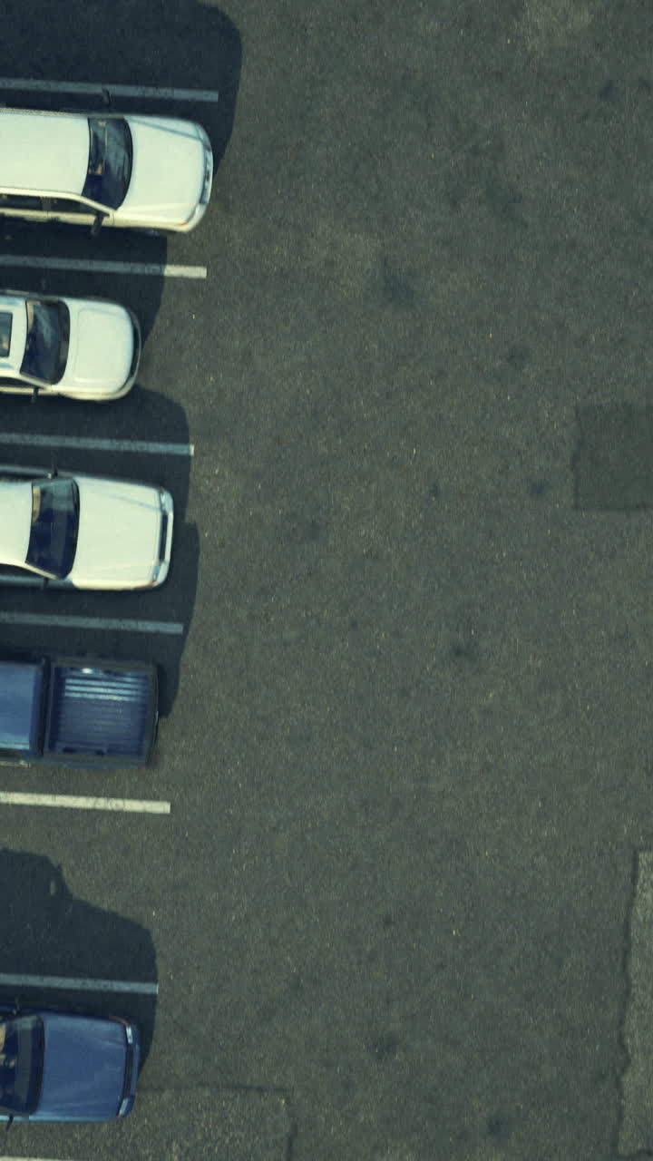 Birds eye view of a busy parking lot with various parked cars during daylight