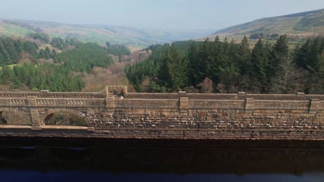 Aerial-View-Of-People-Crossing-On-Scar-House-Reservoir-Architectural-Structure-In-Yorkshire,-England