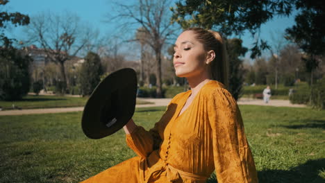 stylish young woman sitting in the grass outdoors.