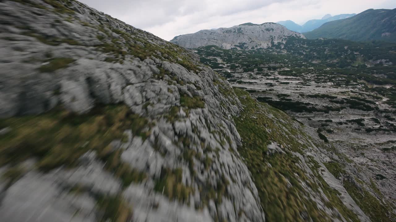 Rapida immersione FPV sopra scogliere rocciose a Tauplitz, che termina su un lago incastonato tra verdi montagne alpine.