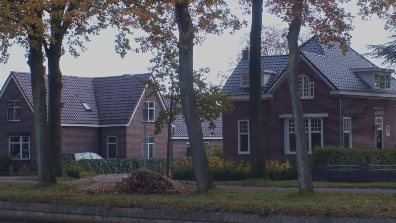 casas clásicas tradicionales en el pueblo de los países bajos holanda en el otoño otoño con, árboles y hojas al lado de la calle tranquila camino