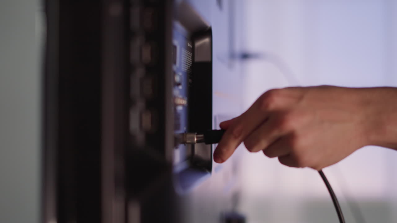 el hombre enchufa el cable a la televisión inteligente en un fondo borroso