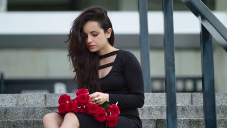 closeup woman sitting with roses. woman touching bouquet of roses on stairs