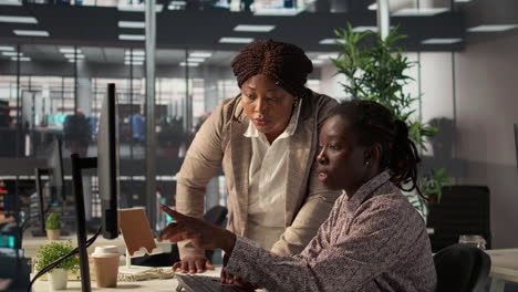 two black women collaborating on a computer in the office