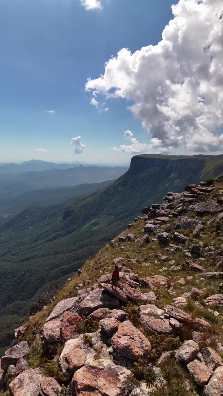 Scatto aereo dall'alto di un escursionista solitario in piedi sul bordo roccioso della spettacolare parete rocciosa di Tundavala Gap che si affaccia su una vasta valle a Lubango, Provincia di Huíla, Angola meridionale