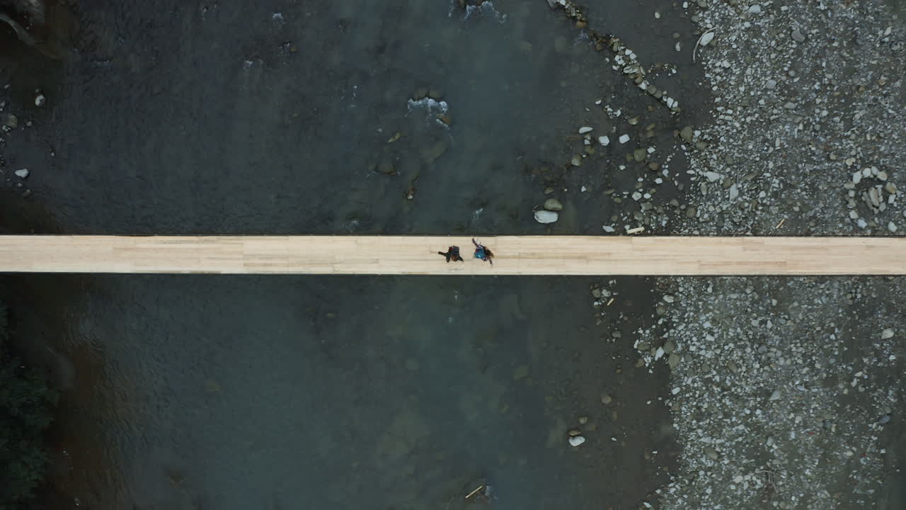 젊은 부부가 강을 가로지르는 서스펜션 브릿지 위에서 춤을 추고 서로 즐기고 있습니다.