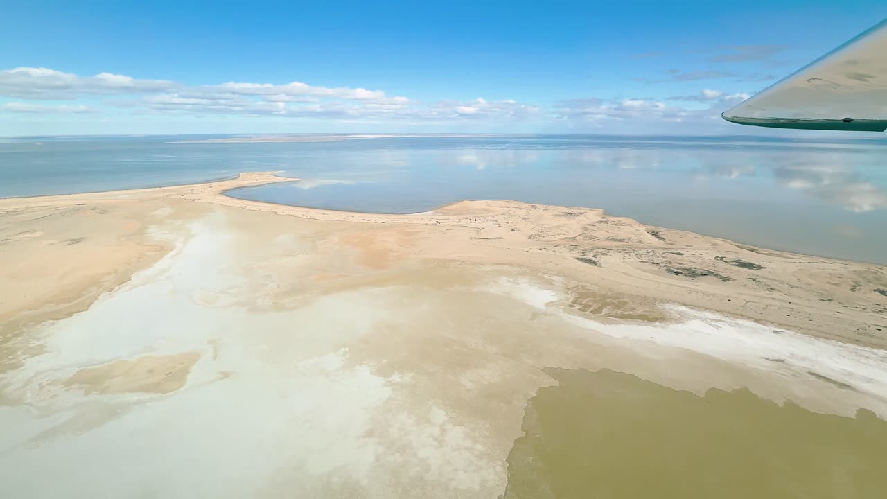 Aerial footage captured from a Cessna aircraft over Lake Eyre in the South Australian Outback. Witness the beautiful sight of this salt lake filling with water, reflecting the serene blue sky.