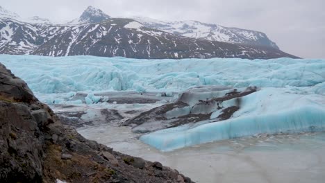 estática, toma de la costa turquesa, glaciar skaftafellsjokull, montañas nevadas al fondo, en un día nublado, en la costa sur de islandia
