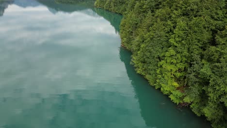 Calm-relaxing-aerial-view-of-Klontalersee-lake-adorned-by-Alpine-trees