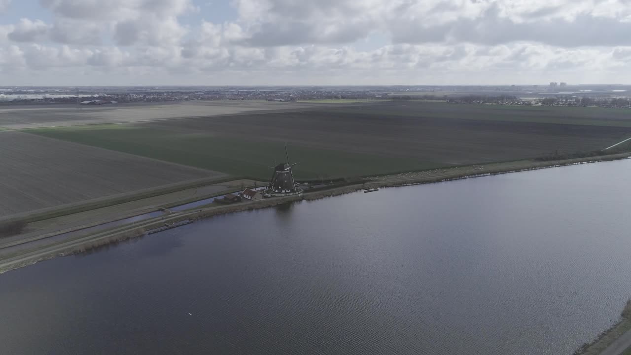 toma de un gran río con un molino de viento holandés en la orilla del río