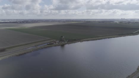 Drone-shot-of-big-river-with-a-Dutch-windmill-on-the-riverbank