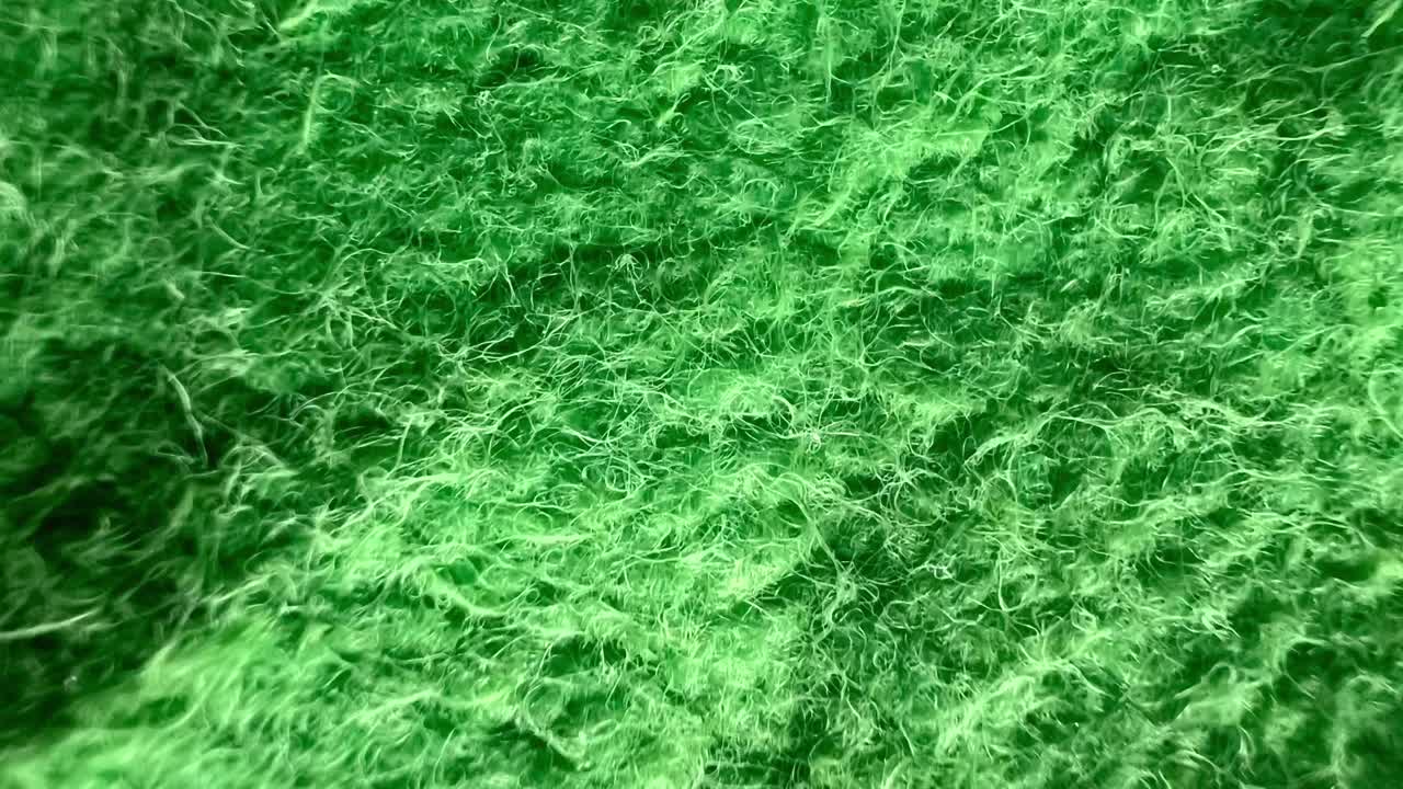 Soft green wool fabric creating a wavy texture, providing a cozy and inviting background ideal for various textile, fashion, and design projects. Perfect for enhancing warmth and comfort