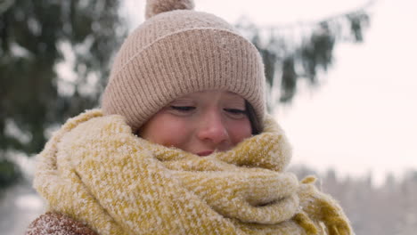 close up view of a girl in winter clothes holding a snowball with her hand