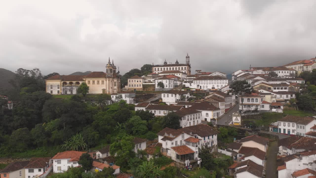 Aerial rotating pan showing the city centre of Ouro Preto, Minas Gerais, Brazil, with typical colonial architecture against an overcast sky with heavy clouds