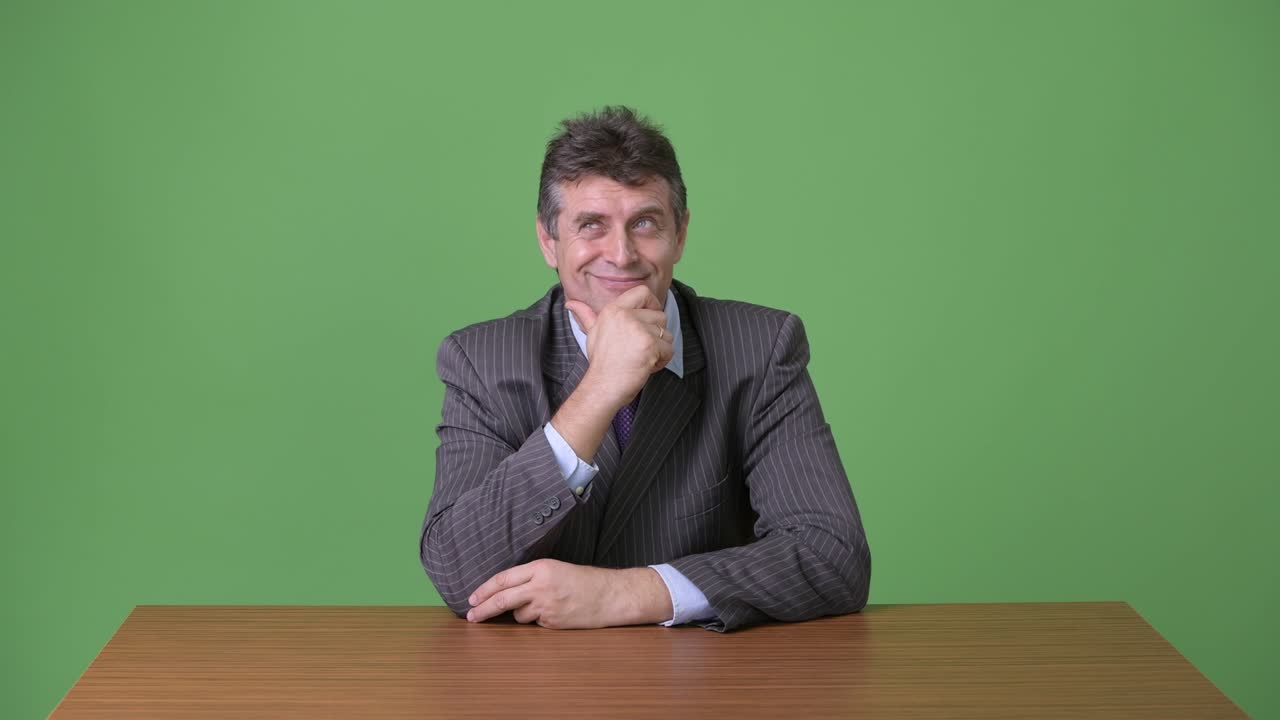 hombre de negocios maduro y guapo contra un fondo verde