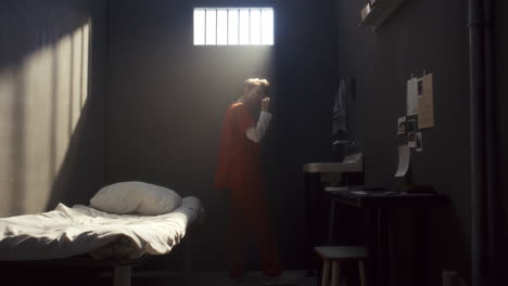 female inmate brushing teeth in prison cell bathed in morning sunlight