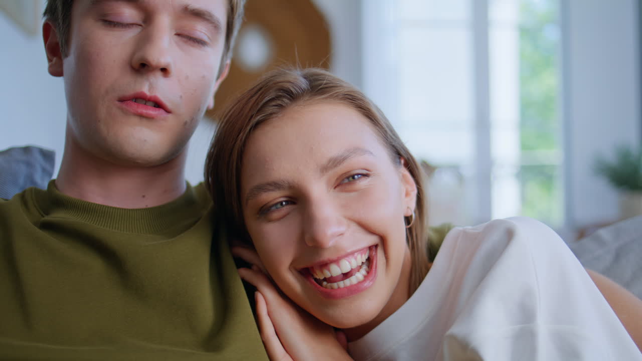 Laughing woman bonding boyfriend watching movie at home closeup. Embracing pair