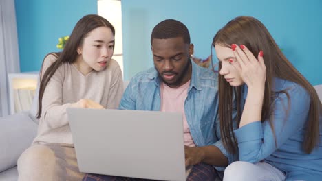 young college friends of different ethnicities working on laptop at home.