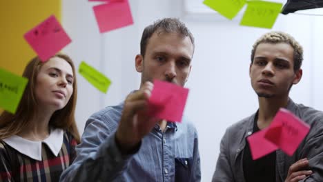 diverse group of finance office worker having corporate training and using glass wall with stickers, slow motion