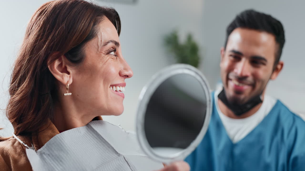 A woman smiles in the mirror after a dental procedure