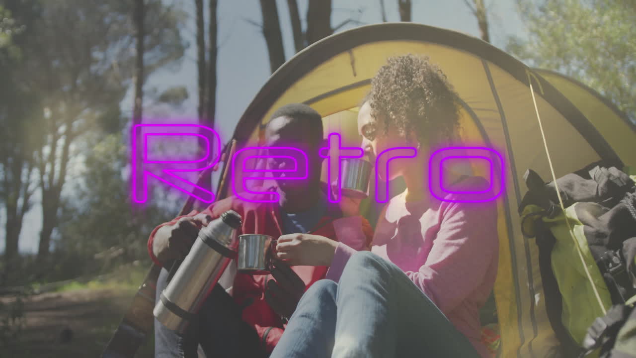 Couple sharing warm drink at yellow tent with neon-pink retro overlay for travel marketing