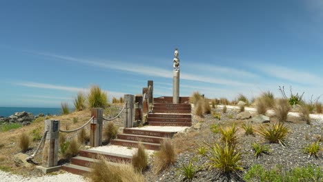 una estatua maorí del jefe tuteurutira se encuentra en la cima de una colina con vistas al océano pacífico