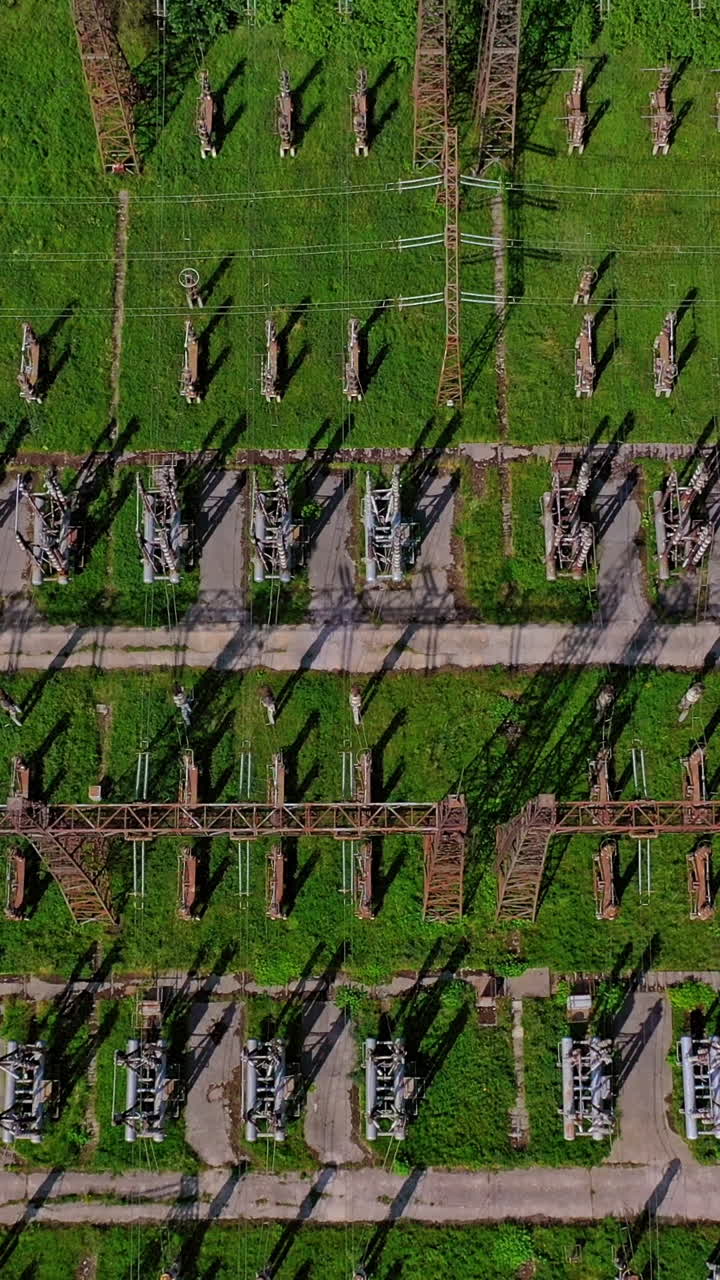 High voltage lines on green field. Flight over power transmission lines. Huge territory with steel pillars for electricity. Top aerial view. Vertical video
