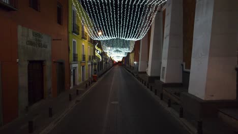 aerial push in footage through the streets of puebla city decorated with christmas lights