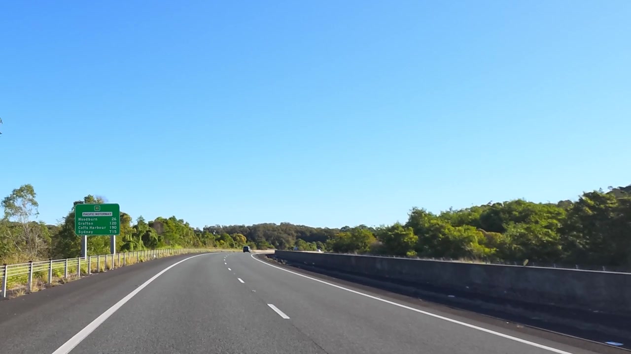 オーストラリアの澄み渡る青空の下、現代的なアスファルトの高速道路を運転する一人称視点の映像