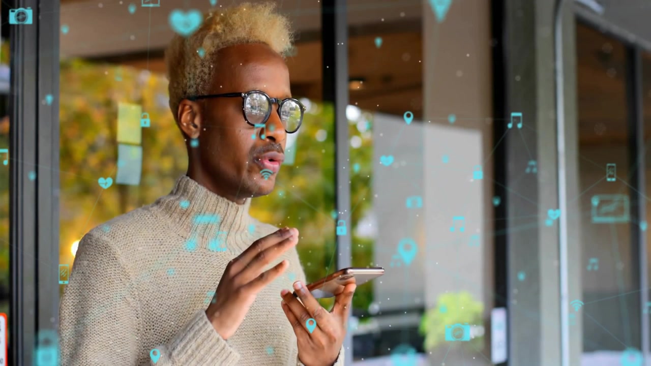 Man using smartphone by glass panel, showcasing tech workflow with floating icons and sticky notes