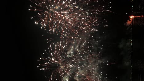 explosiones alternas de luces coloridas estallando en el cielo nocturno frente a una playa en un famoso distrito turístico en un país del sudeste asiático