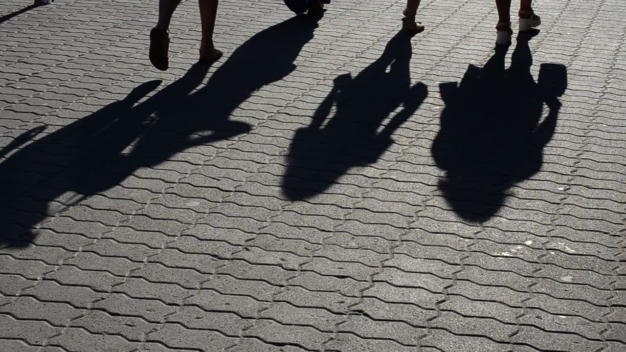 Luce e ombra, riflesso di persone nei raggi del sole al tramonto. Persone e le loro ombre