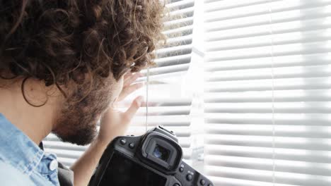 photographer looking through window blinds