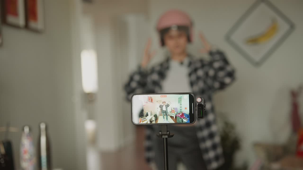 Jovem mulher gravando vídeo com smartphone e capacete rosa