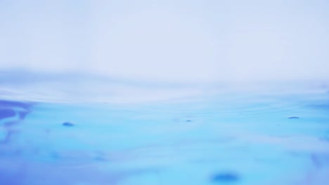 the clean water surface in slow motion fills the screen with water splashing shop the water drop and waving liquid surface with an air bubble