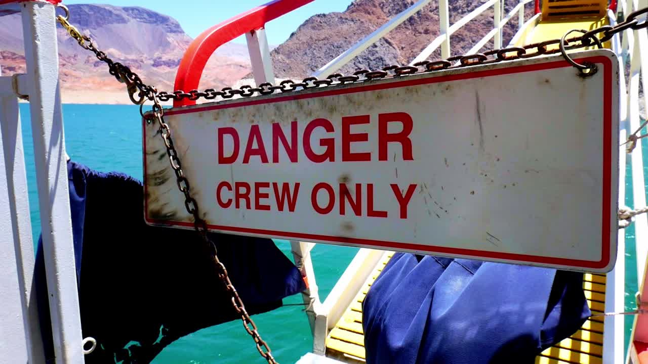 Danger Crew Only sign swinging on a boat with rusty chains