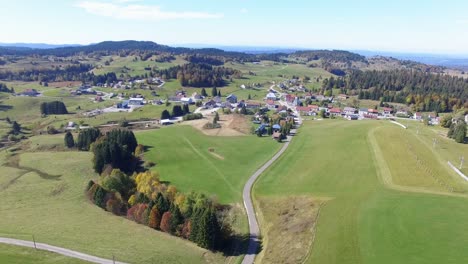 Luftflug-Mit-Dorf-La-Pesse-Und-Juragebirge-Im-Hintergrund-Im-Sommer,-Frankreich