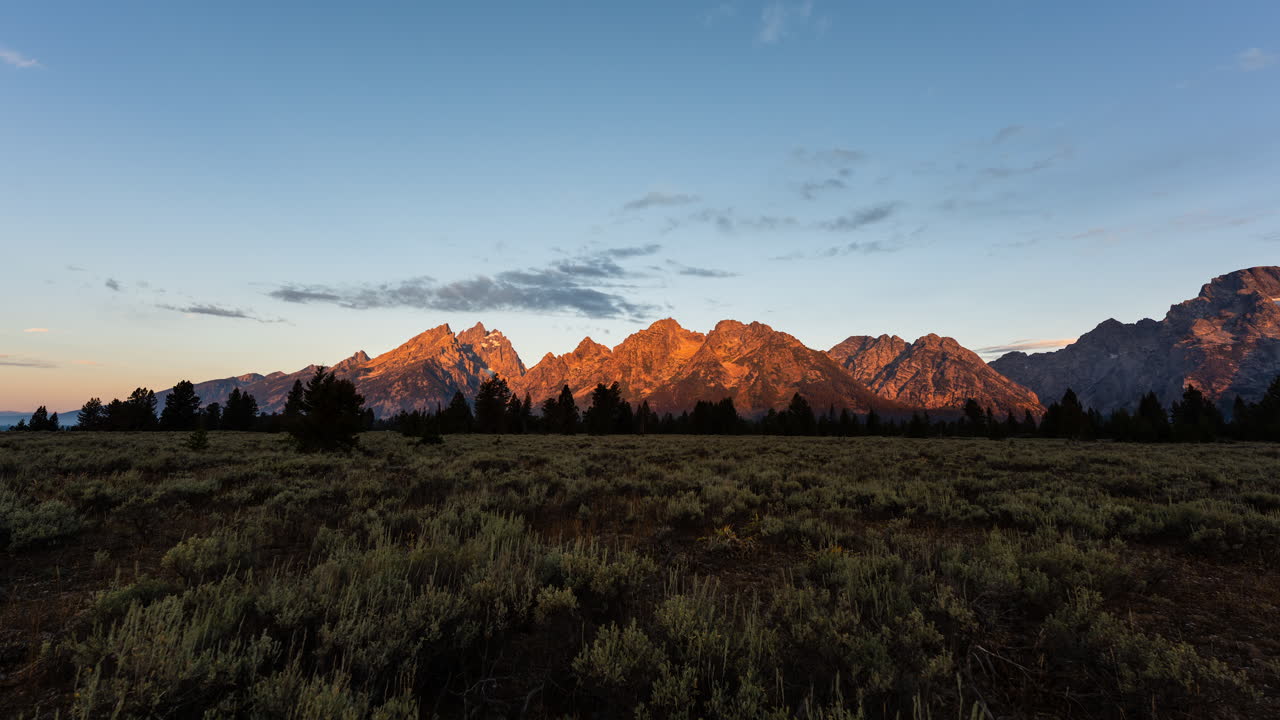 Sunrise over a majestic mountain range and expansive field
