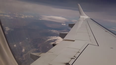 airplane passenger wing over mountains with snow