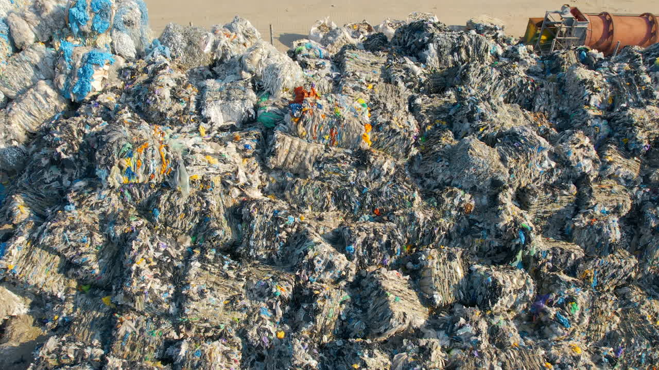 Drone view of huge heaps of pressed garbage at waste sorting plant. Slow motion