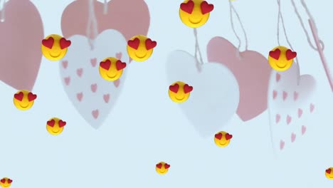 Multiple-heart-eyes-face-emojis-floating-against-hanging-heart-shape-decorations