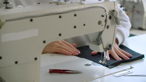 sewing machine needle in motion. close-up of sewing machine needle rapidly moves up and down. the tailor sews black fabric on the sewing workshop. the process of sewing fabric.